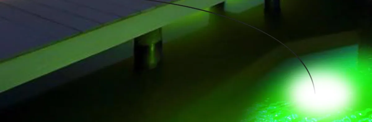 A green glow in the water beside a dock at night