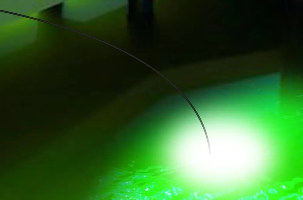 A green fishing light glowing under the surface beside a dock